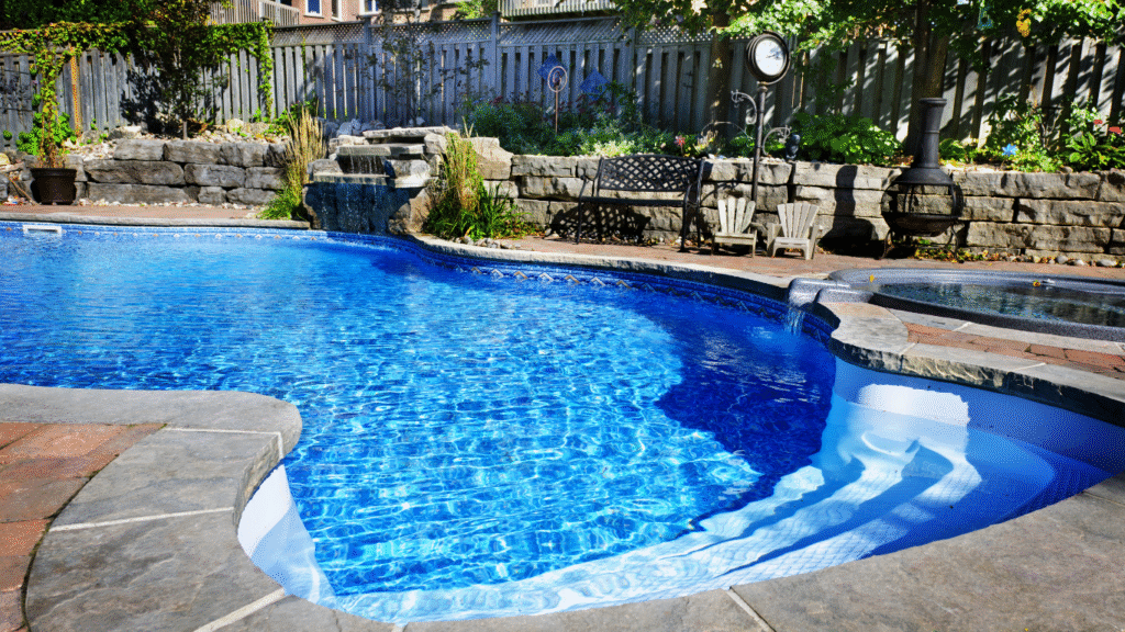 Backyard swimming pool with stone retaining walls and a small waterfall